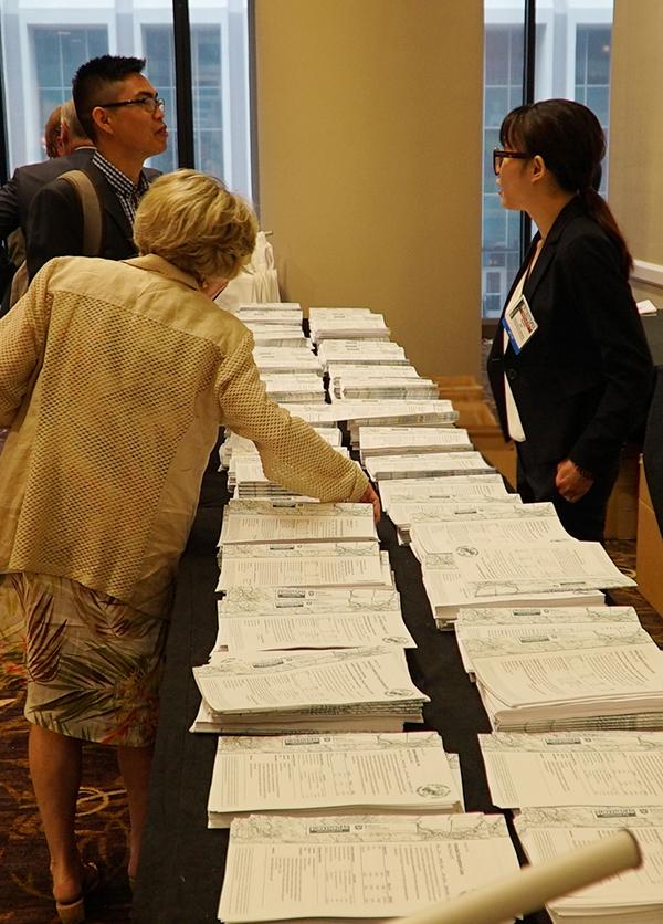 photo of people at the Burkenroad Reports Research Conference reviewing the printed copies of the reports.