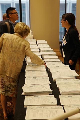 photo of people at the Burkenroad Reports Research Conference reviewing the printed copies of the reports.